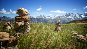Ein Bergpanorama von einer Weide aus gesehen, mit kleinen aufgetürmten Steinhäufchen